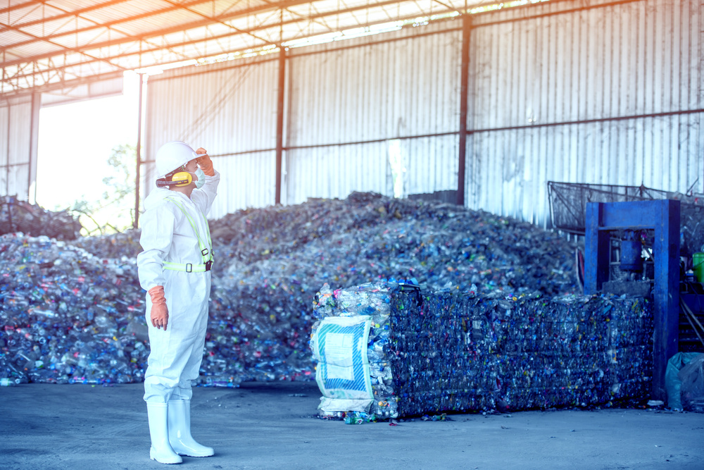 Industrial Plastic, Thermoforming & More - Seraphim Plastics - Bales of plastic bottles at processing plant behind worker.